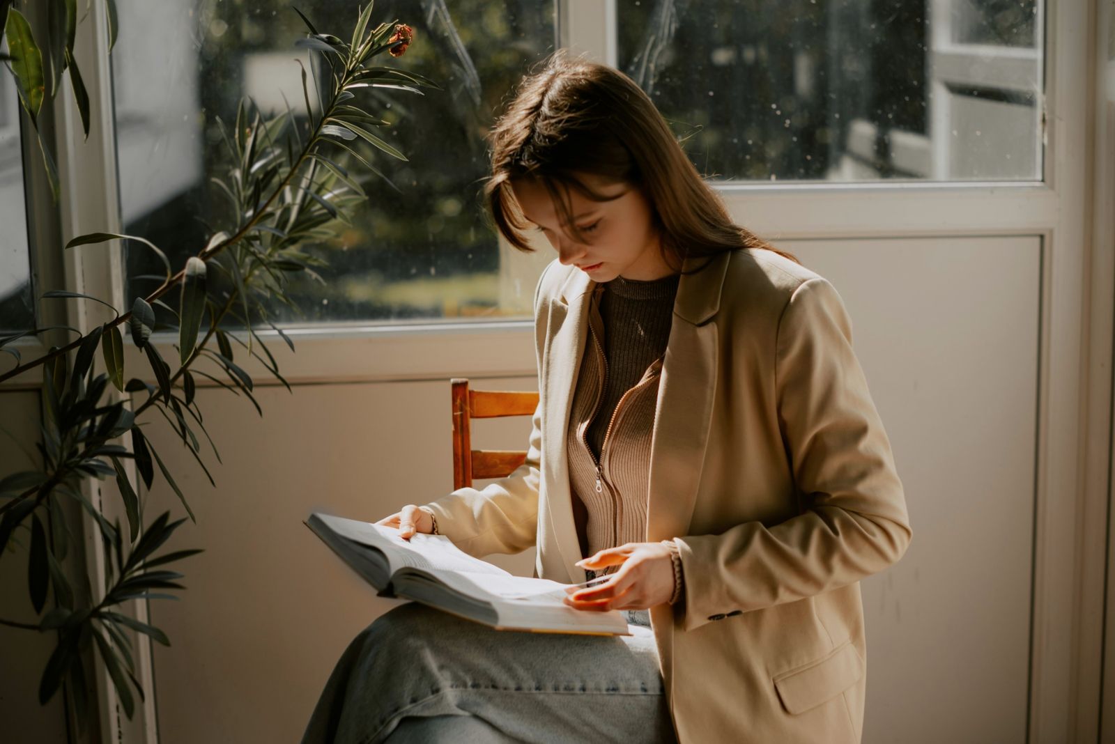 A woman reading by a window with plants